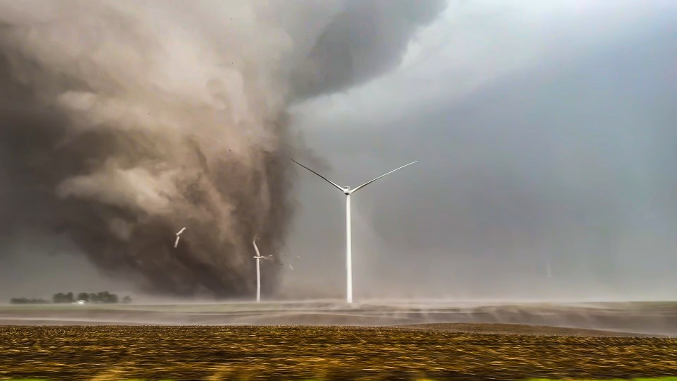 a wind turbine is in the foreground of a tornado