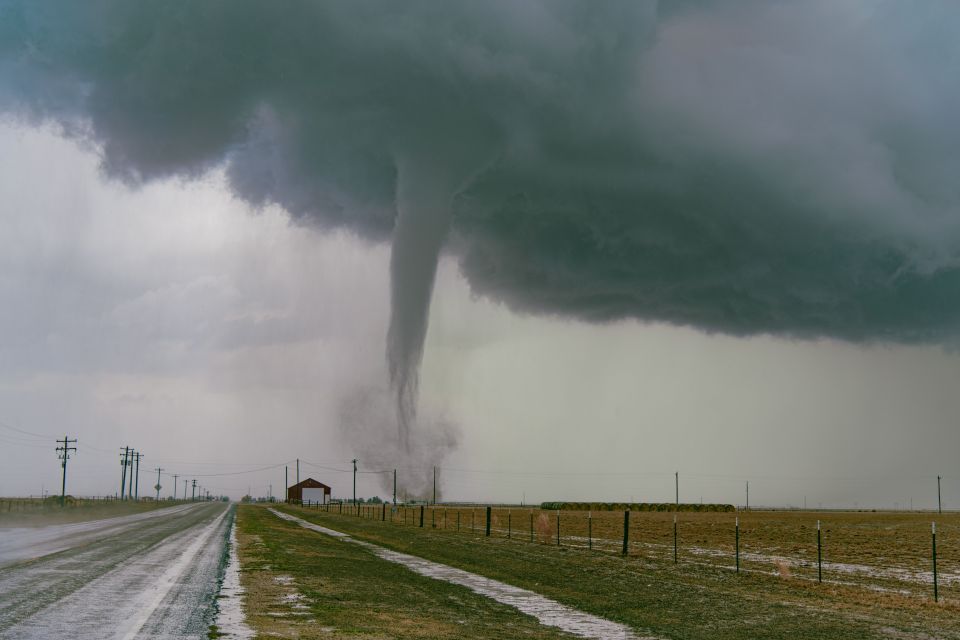 a tornado is coming down a road near a barn