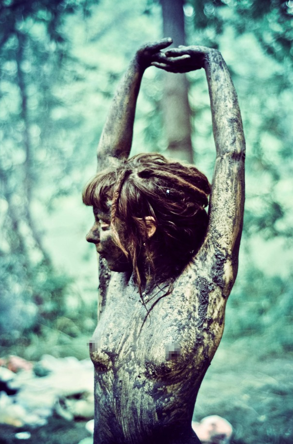 a woman with dreadlocks is covered in mud and has her arms outstretched