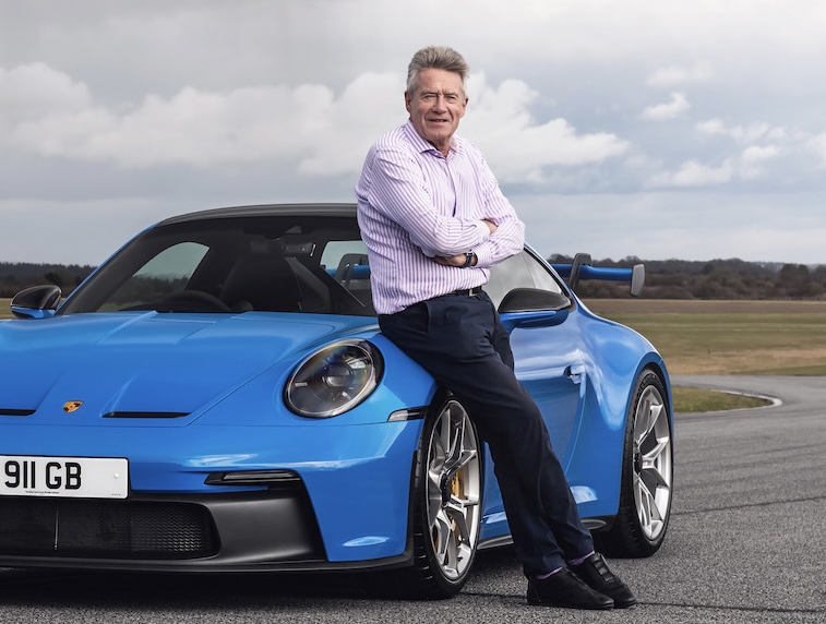 a man leans on the side of a blue porsche