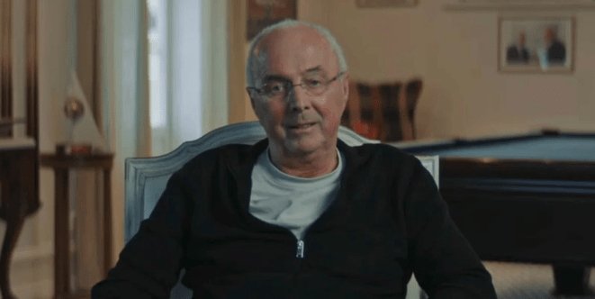 a man wearing glasses is sitting in a chair in front of a pool table