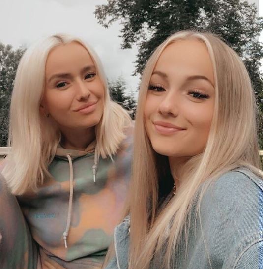 two blonde women are posing for a picture together and smiling for the camera .