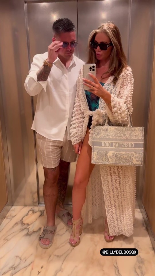 a man and a woman are taking a selfie in an elevator and the woman is holding a dior bag