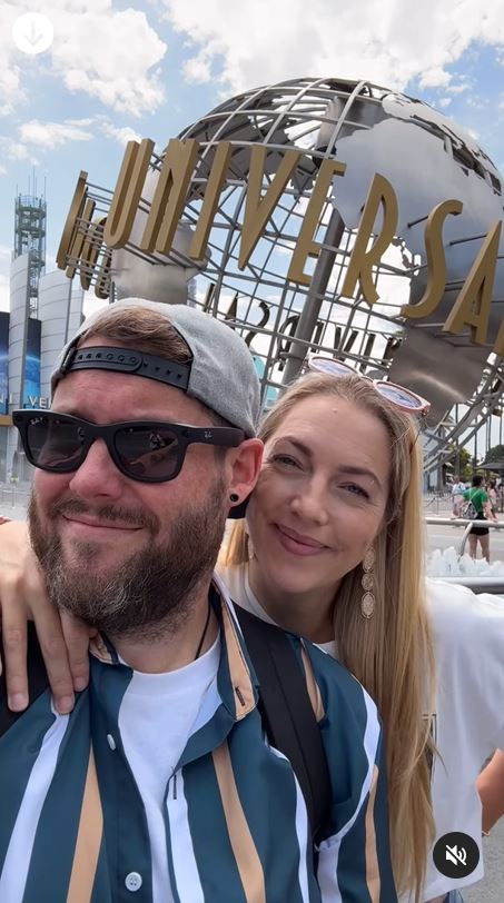 a man and woman pose in front of a universal studios sign