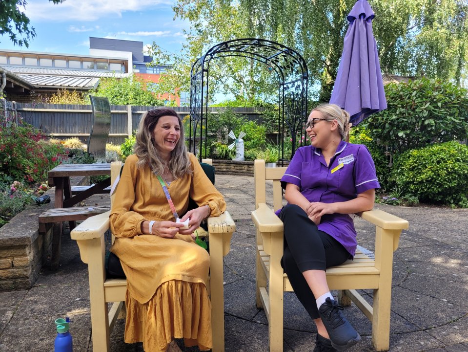 a woman in a yellow dress sits next to a nurse in a purple uniform