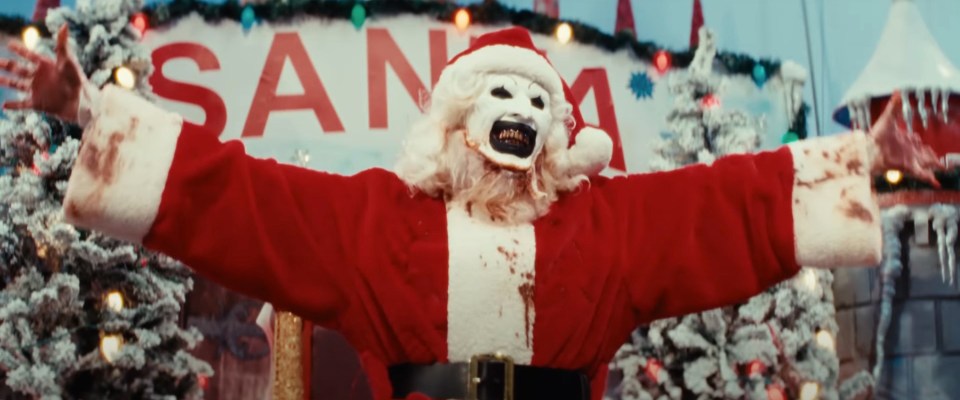 a man dressed as santa claus with his arms outstretched in front of a sign that says santa