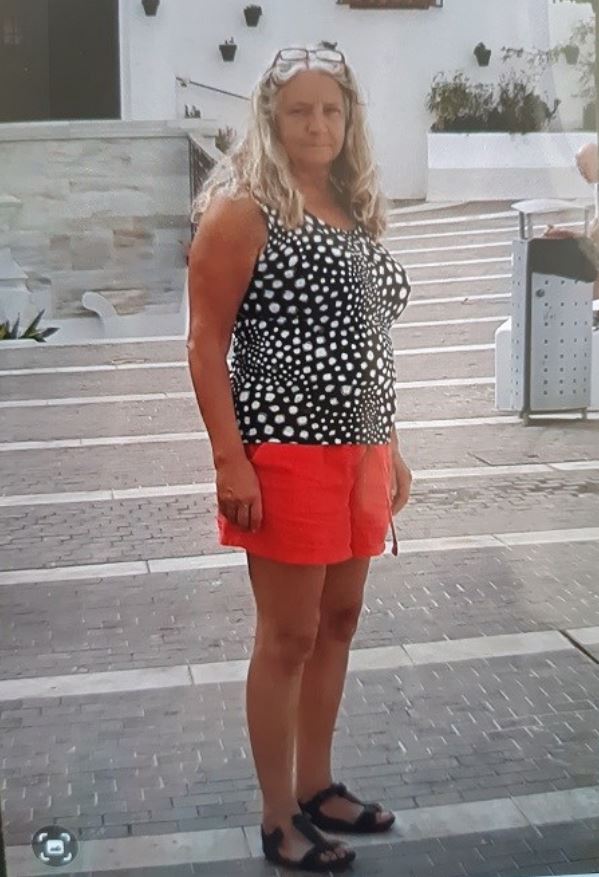 a woman in a black and white polka dot tank top and red shorts