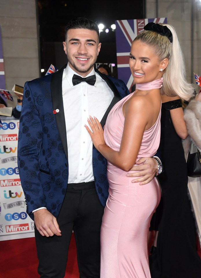 a woman in a pink dress stands next to a man in a blue suit