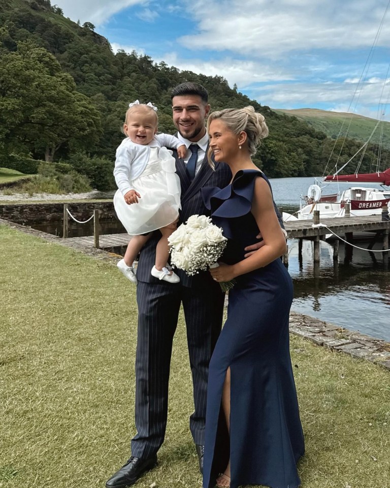 a woman in a blue dress stands next to a man and a little girl