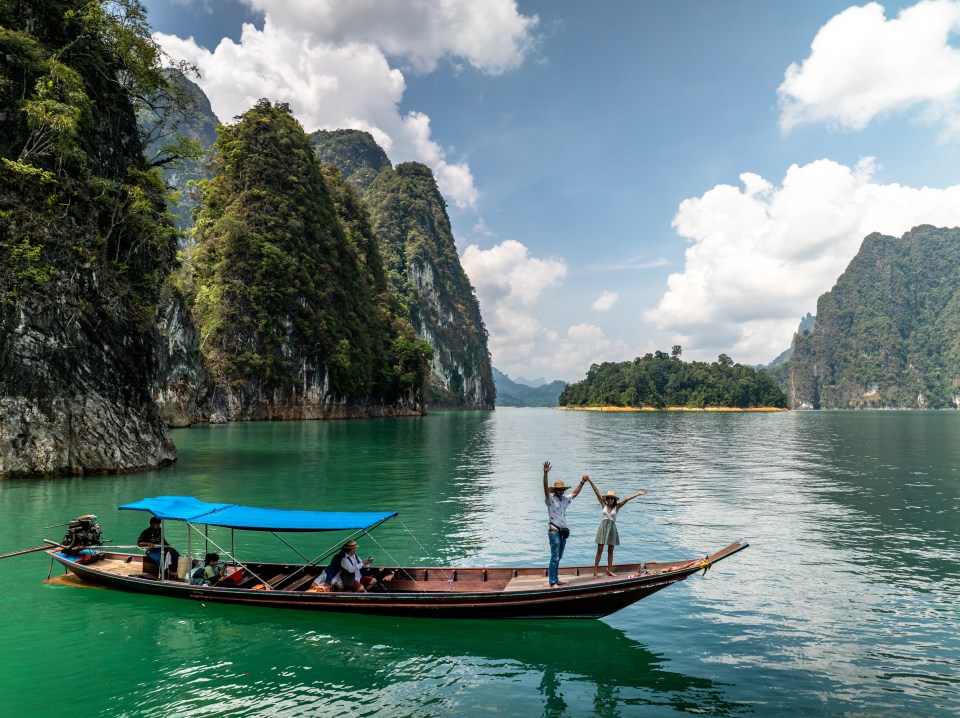 a couple in a boat on a lake holding hands