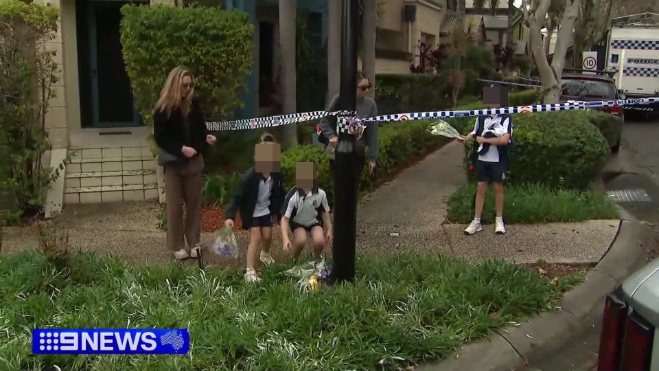 a group of people are standing in front of a house with a news headline