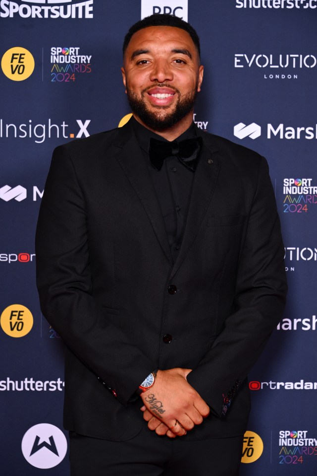 a man in a suit stands in front of a wall that says sport industry awards