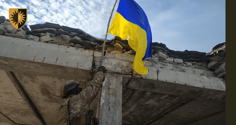 a soldier holds up a blue and yellow flag