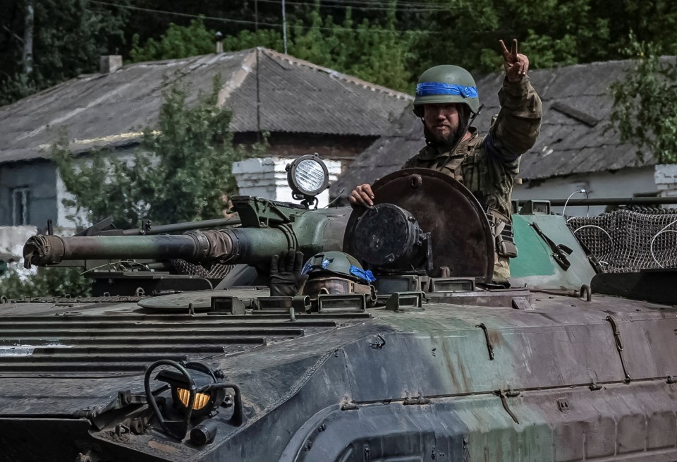 a soldier in a tank giving a peace sign