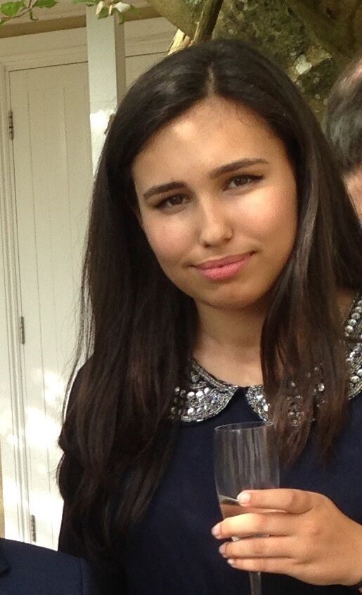 a woman with long dark hair is holding a glass of wine