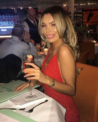 a woman in a red dress is sitting at a table holding a glass of champagne .