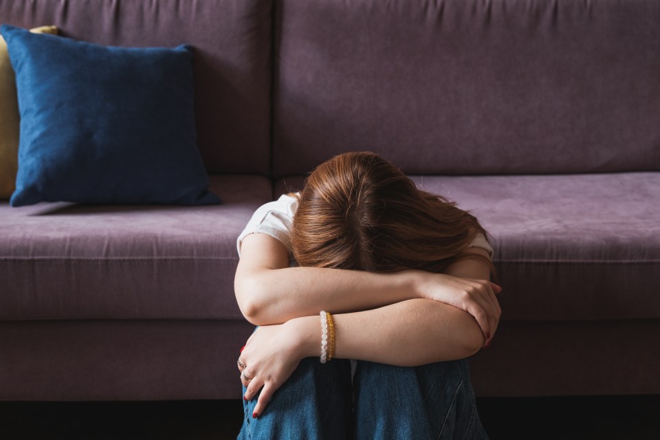 a woman sits on a couch with her head down