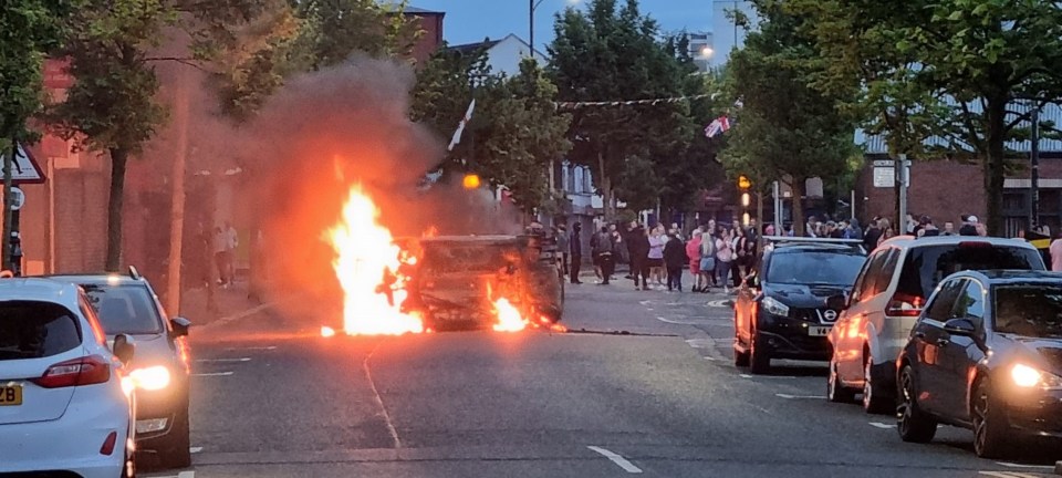 A vehicle was last night set alight outside Belfast City Hall as rampaging thugs took to the streets