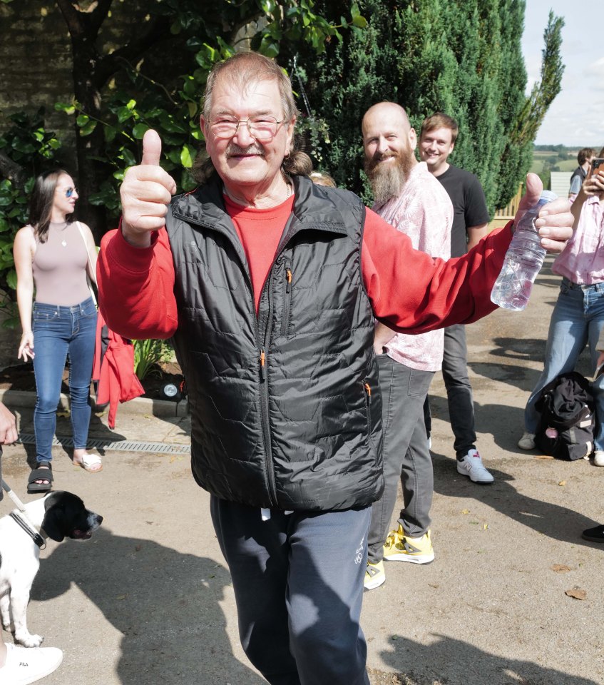 a man in a black vest is giving a thumbs up