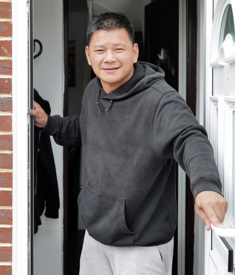 a man in a black hoodie is standing in front of a door