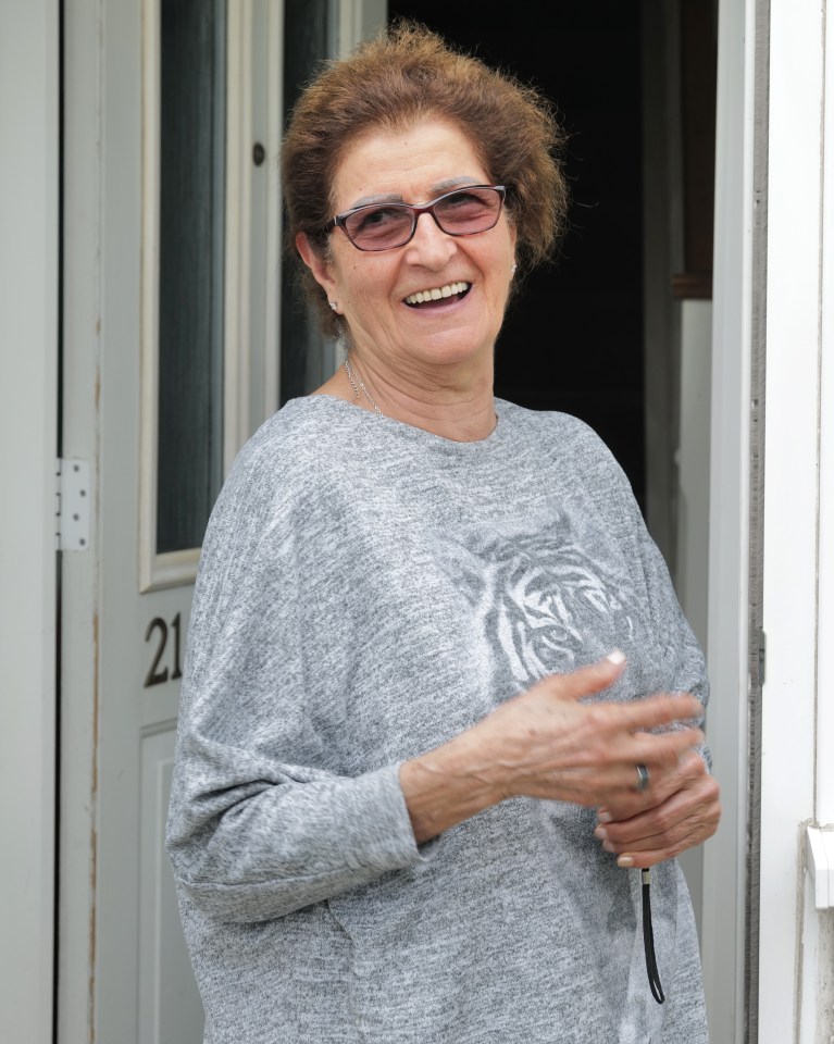 a woman wearing a grey shirt with a tiger on it stands in front of a door with the number 21 on it