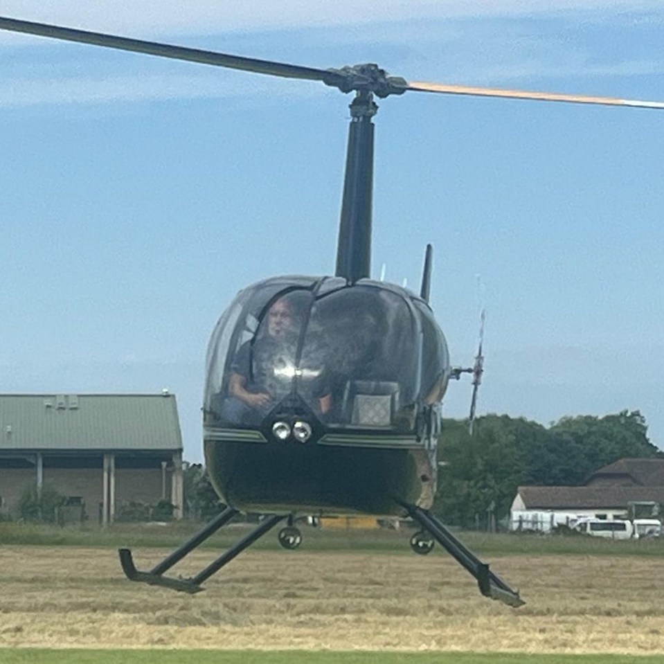 a small black helicopter is flying over a field