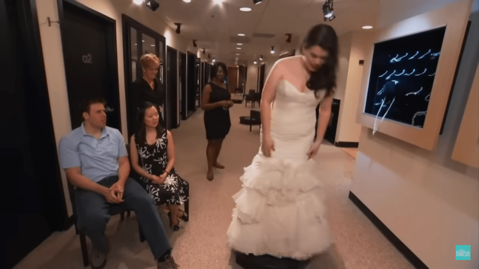 a woman in a wedding dress is standing in a hallway with other people