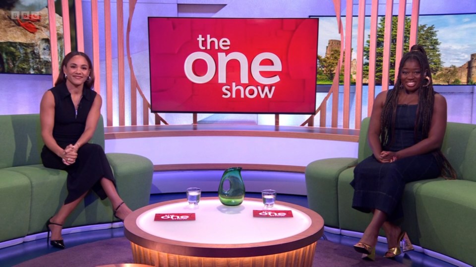 two women sit in front of a red sign that says the one show