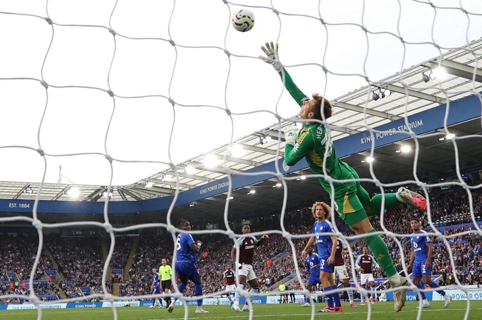 a soccer player jumps to catch a ball in front of a sign that says king power stadium