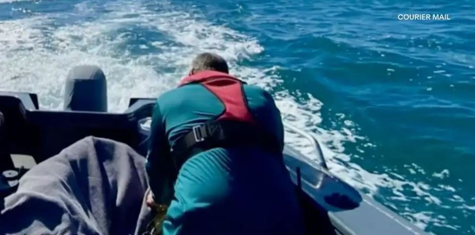 a man in a life jacket is riding a boat in the ocean .