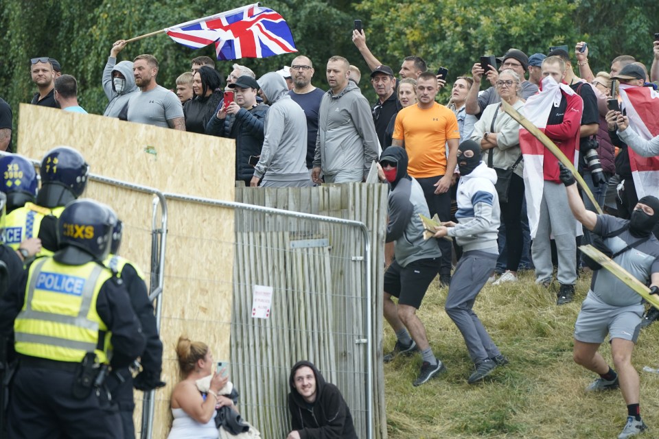 A woman and a man take cover as objects are lobbed towards police in an anti-immigration demonstration in Rotherham