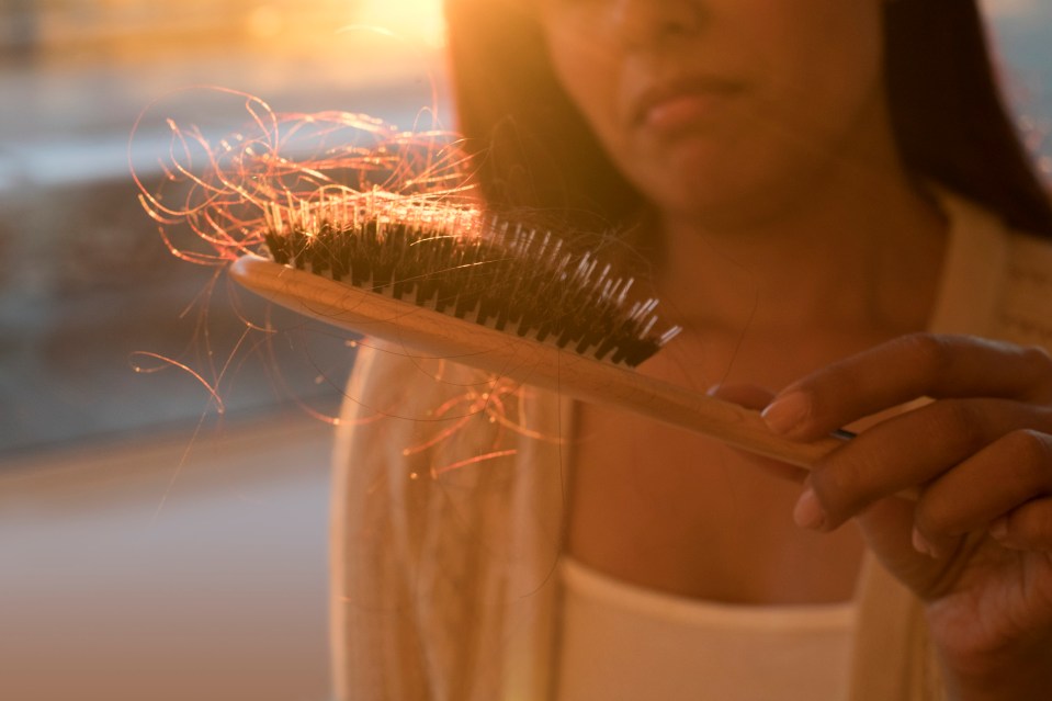 a woman is holding a brush with a lot of hair on it