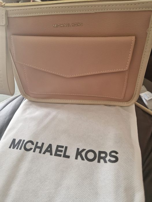 a michael kors bag is sitting on a white cloth