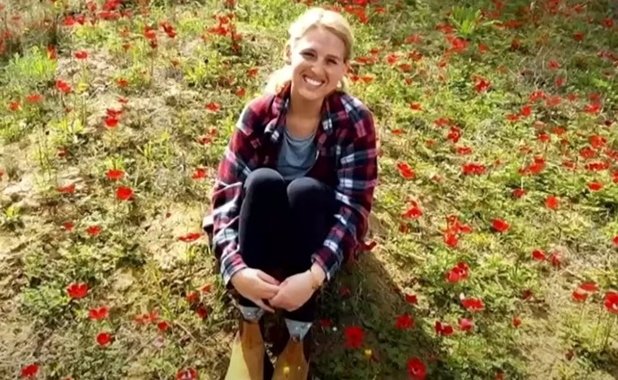 a woman is sitting on the ground in a field of red flowers .