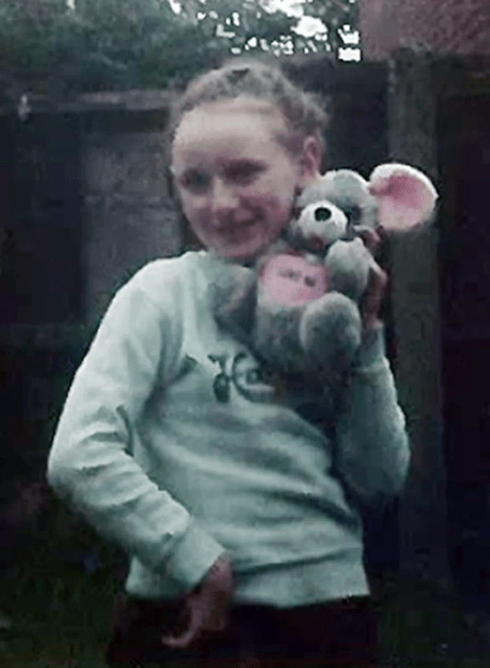 a young girl is holding a stuffed mouse in her arms .