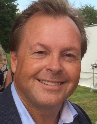 a man in a suit and blue shirt is smiling for the camera .