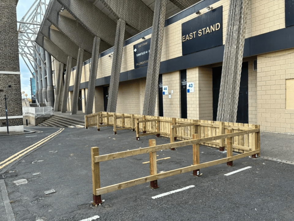 a wooden fence in front of a building that says east stand