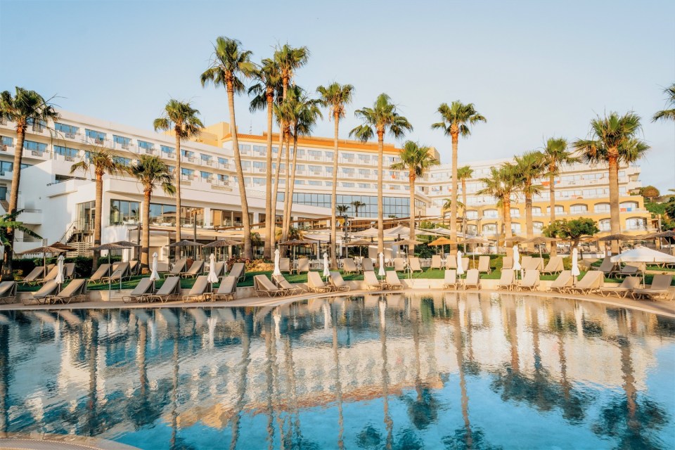 a large swimming pool surrounded by chairs and palm trees