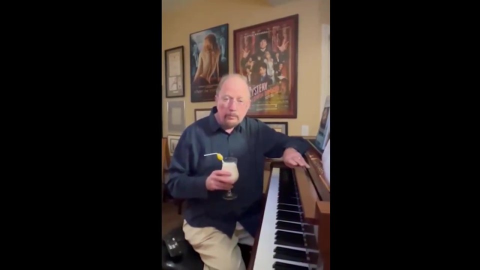 a man playing a piano with a martini in his hand