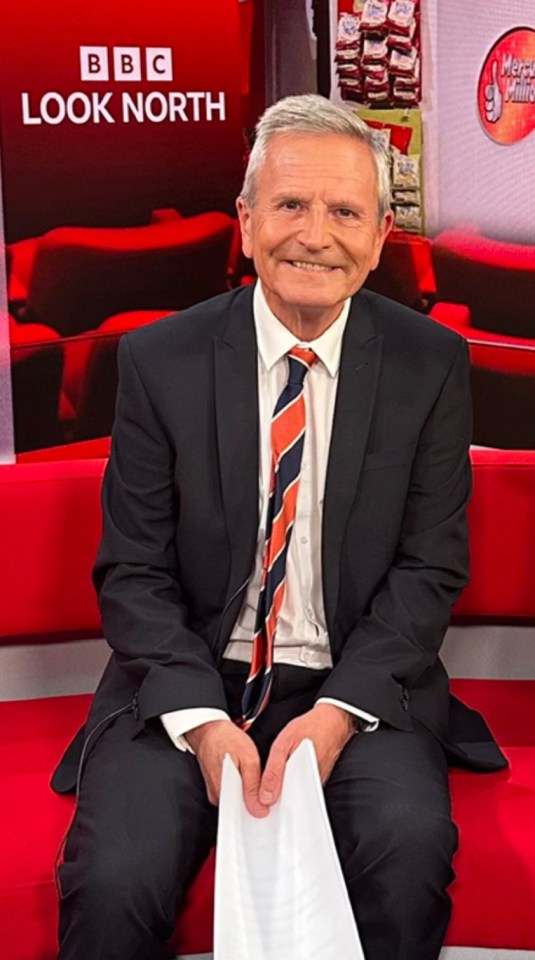 a man in a suit and tie is sitting in front of a sign that says bbc look north