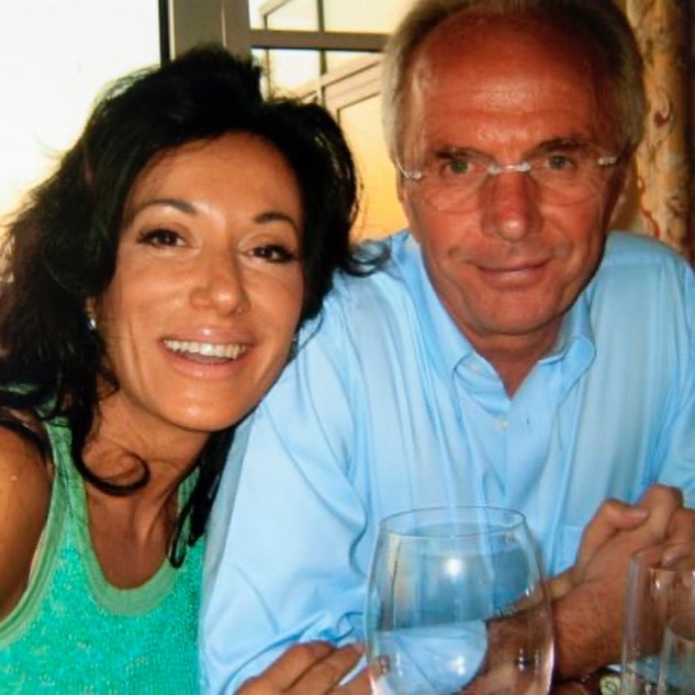 a man and a woman are posing for a picture while holding wine glasses