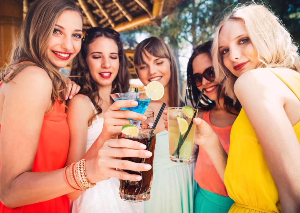 a group of women are holding up their drinks and smiling