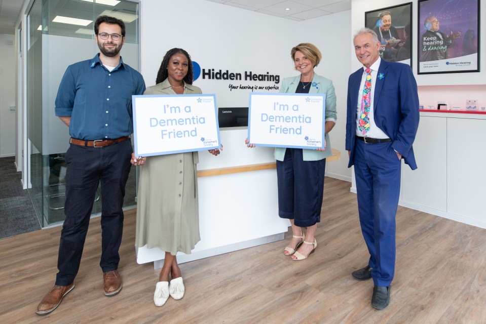 four people holding signs that say i 'm a dementia friend