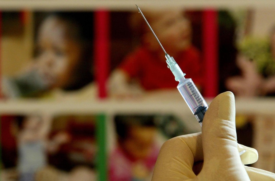 a person holding a syringe with a picture of a child in the background