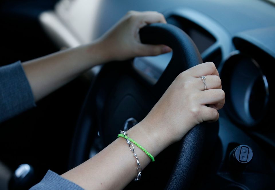 a woman wearing a green bracelet is driving a car