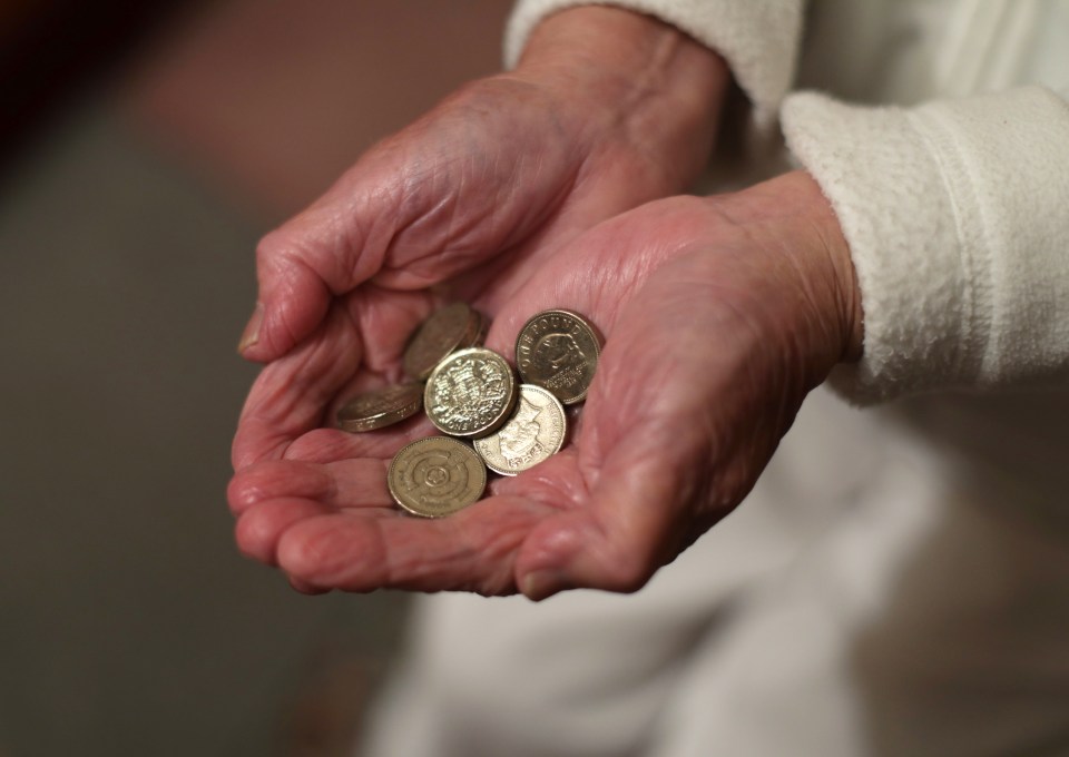 a woman holds a handful of coins including one that says ' elizabeth ii ' on it