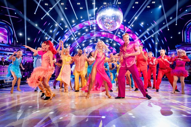 a group of people are dancing on a stage with a disco ball in the background