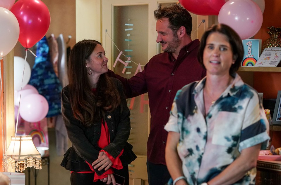 a man and two women are standing in a room with pink balloons