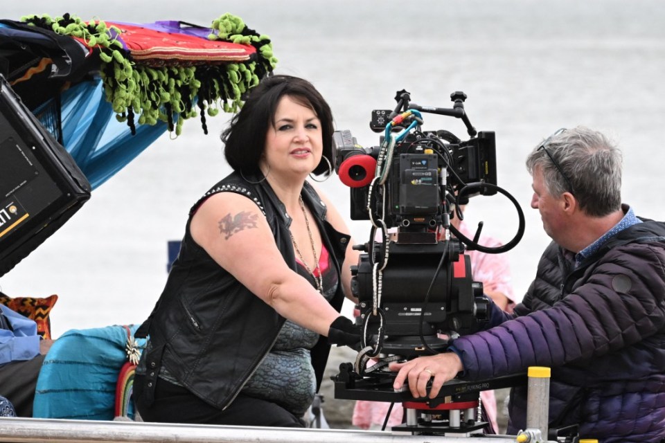 a woman with a dragon tattoo on her arm stands in front of a camera