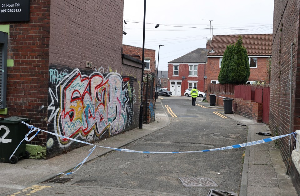 a police officer walks down a street with graffiti on the side of a building